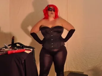 Horny goddess wearing leather and a crimson wig about to pleasure her beaver